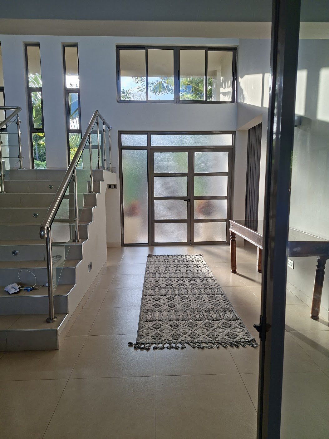 The bright entrance foyer with a patterned rug and staircase